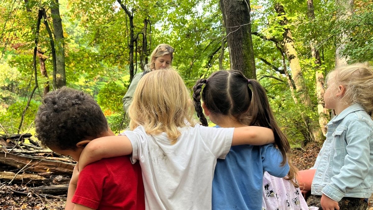 children watching a teacher outside in the woods