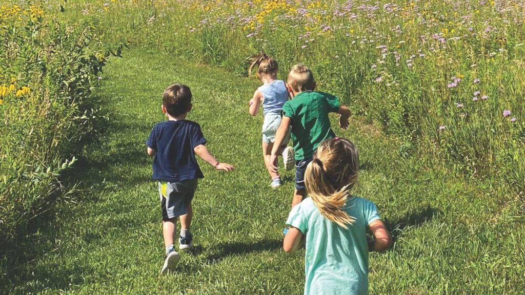 kids running along a mowed pathway through a prairie in summer