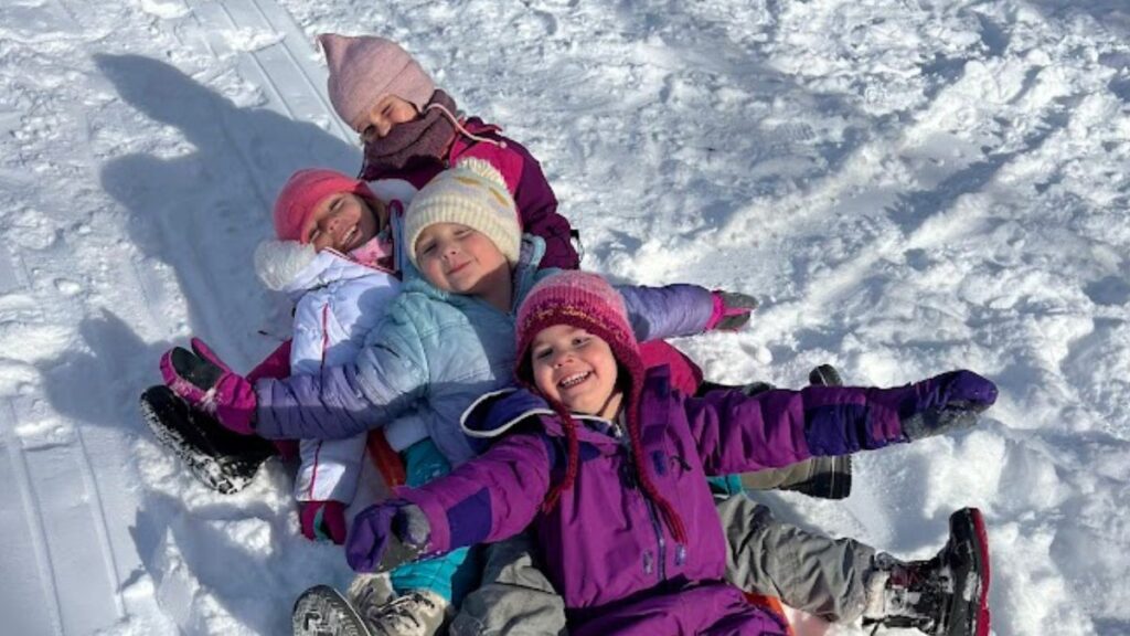 Children in bright coats sledding on a winter day