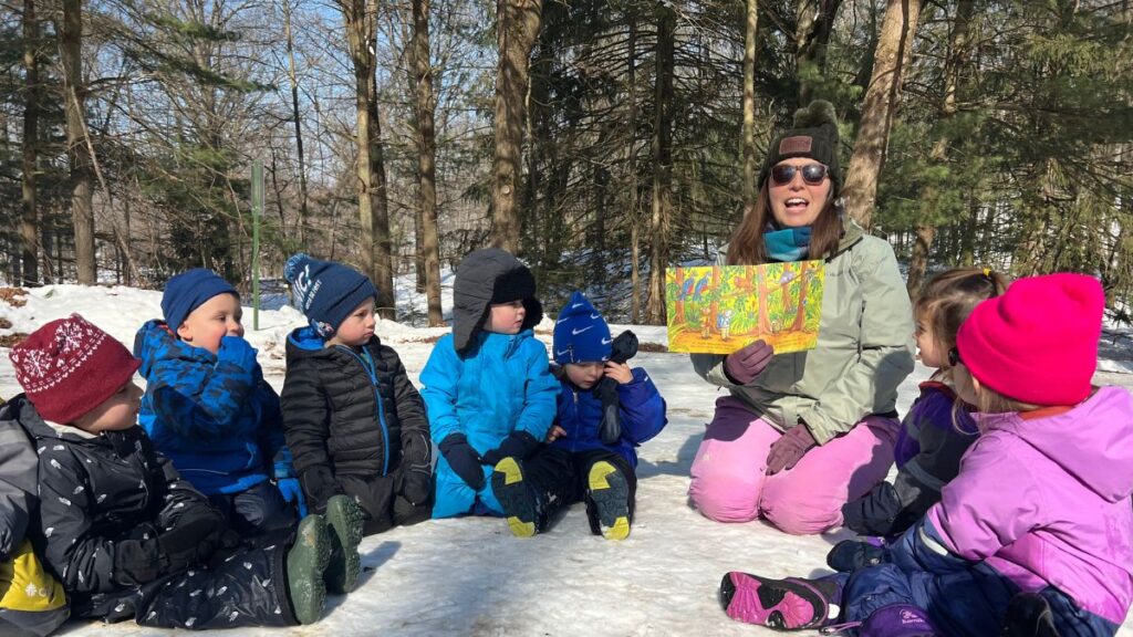 teacher reading to children on a sunny winter day outside