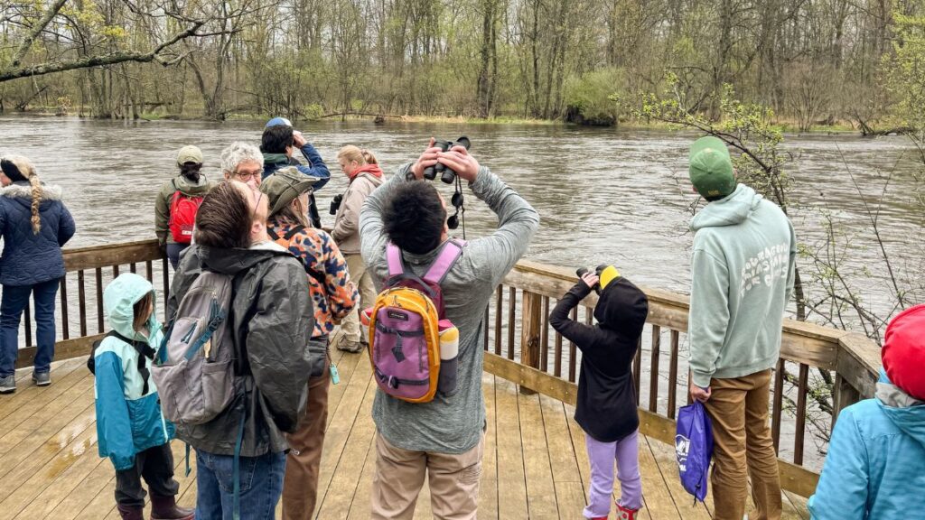 People on a hike with binoculars overlooking a river