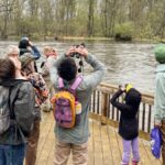 People on a hike with binoculars overlooking a river