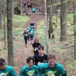 group of people running up a hill in the fall